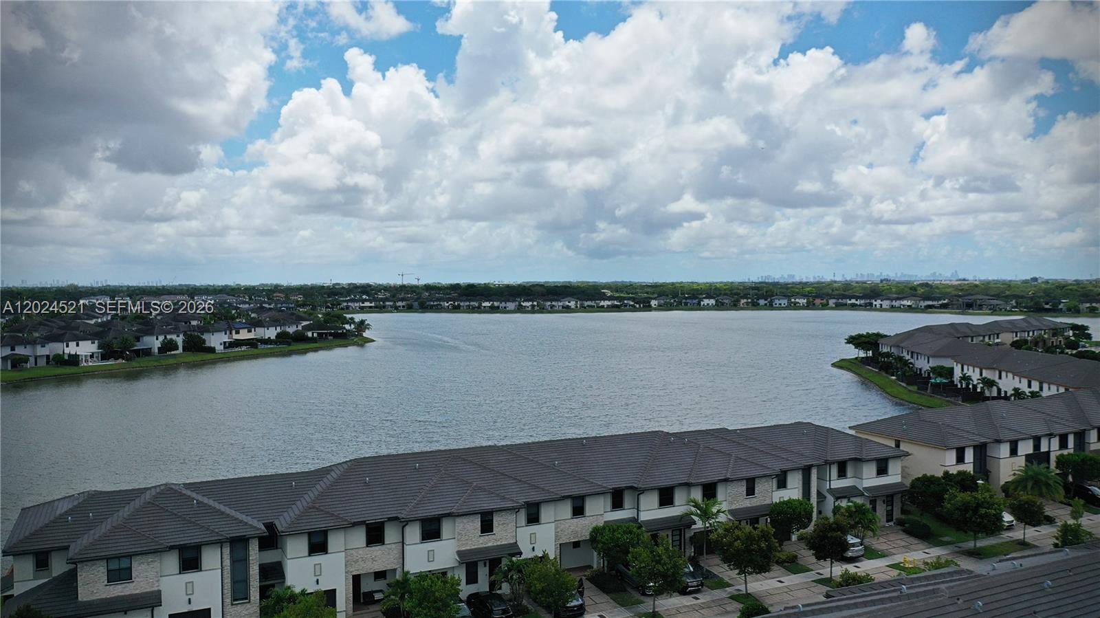 An aerial view shows a large lake surrounded by residential townhomes under a cloudy sky — 16017 NW 91st Ct, Miami Lakes FL 33018, MIAMI LAKES, FL