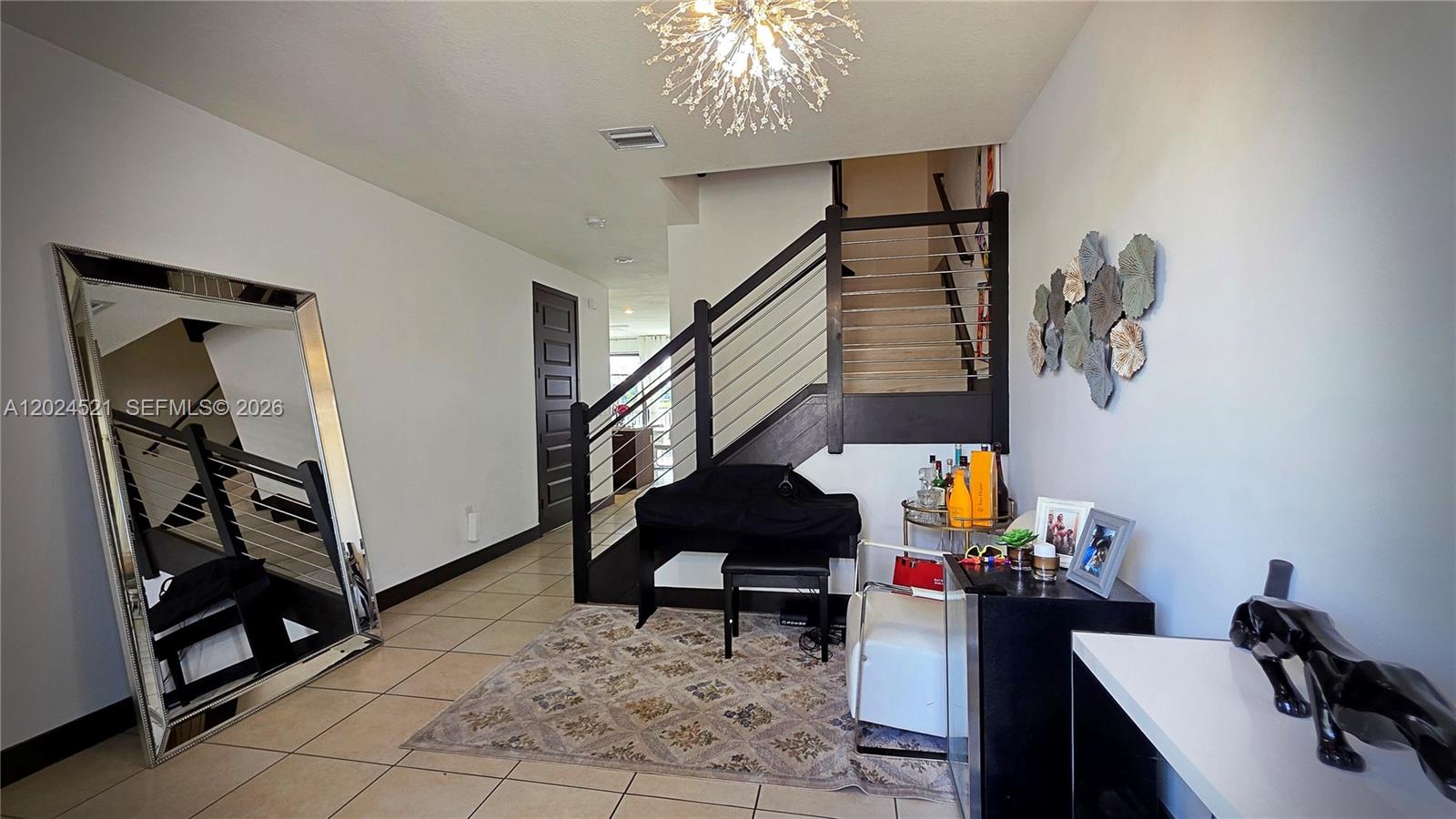 An entryway features a staircase with a dark railing, a large mirror, and tiled flooring — 16017 NW 91st Ct, Miami Lakes FL 33018, MIAMI LAKES, FL