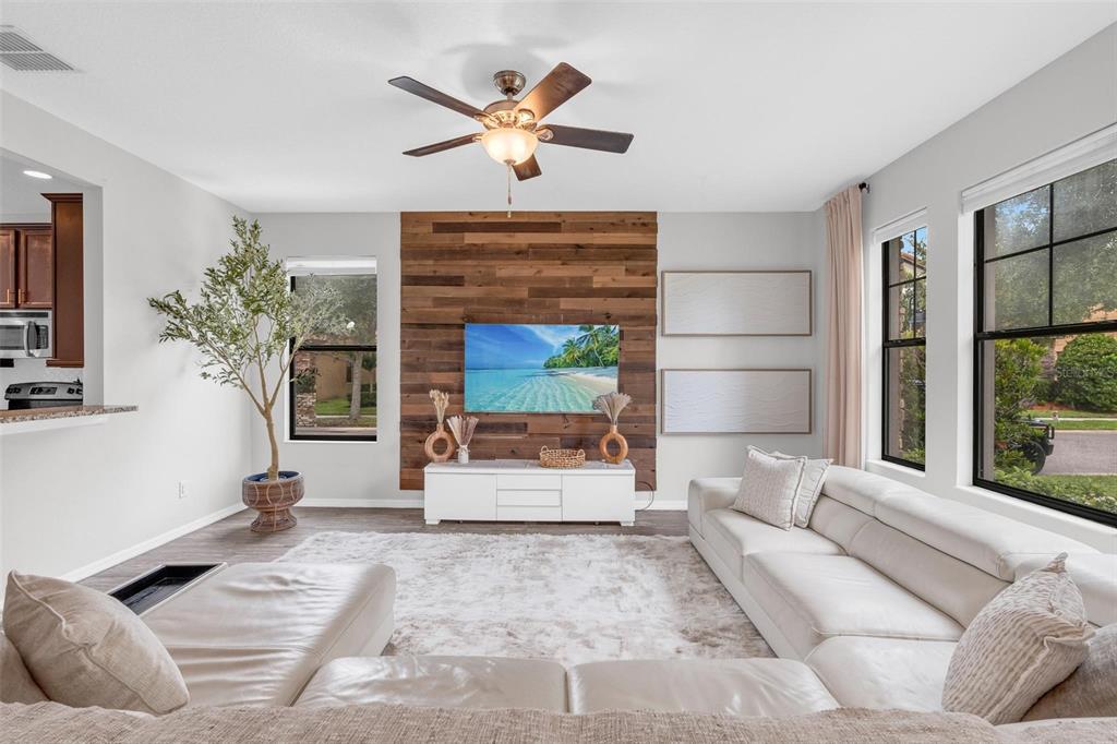 A living room features a wood-paneled accent wall, a white media console, and white sectional — 325 PARTRIDGE PEA LANE, OCOEE, FL