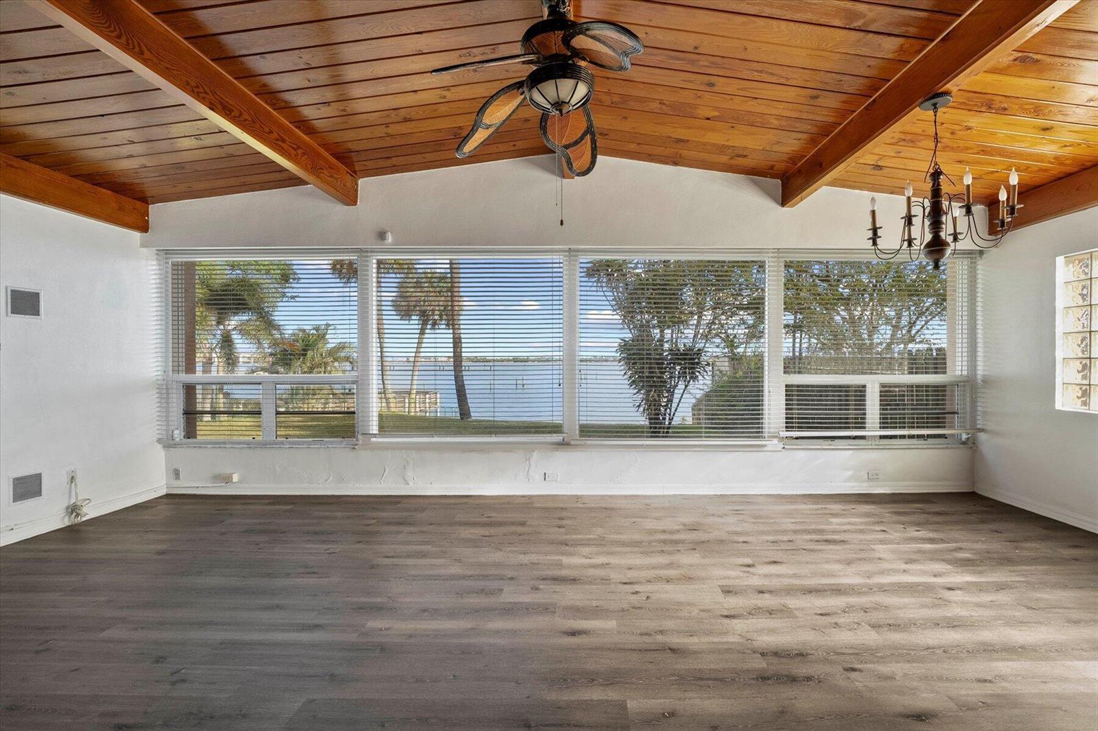 A living room with wood-plank ceilings, wood-look flooring, and large windows overlooking a lake — 101 S Colorado Avenue, Stuart FL 34994, STUART, FL