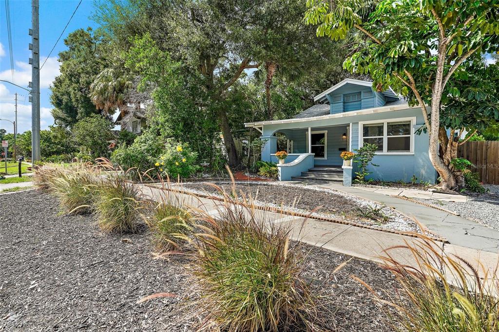 A light blue bungalow with a front porch sits behind a landscaped yard and sidewalk — 2111 BURLINGTON AVENUE N, ST PETERSBURG, FL