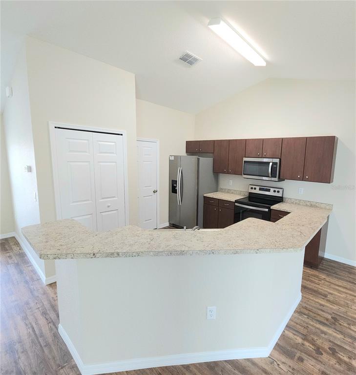 A kitchen with a breakfast bar, stainless steel appliances, and dark wood cabinets — 13775 SW 43RD CIRCLE, OCALA, FL