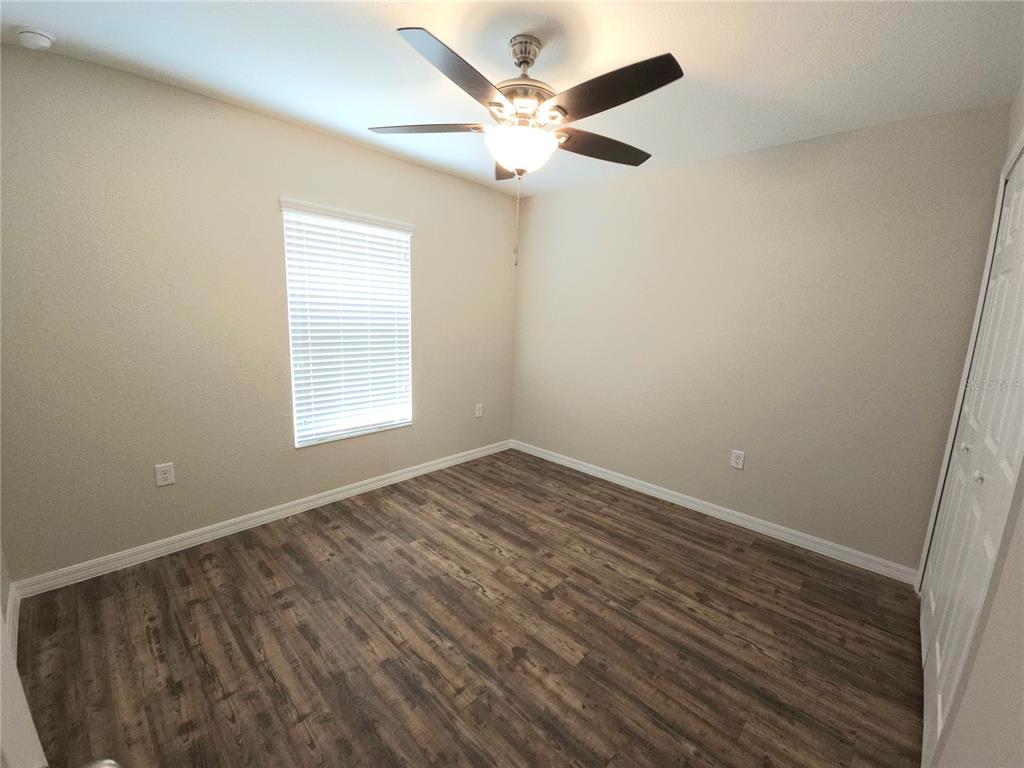 An empty bedroom features wood-look flooring, a ceiling fan, and a window with blinds — 13775 SW 43RD CIRCLE, OCALA, FL