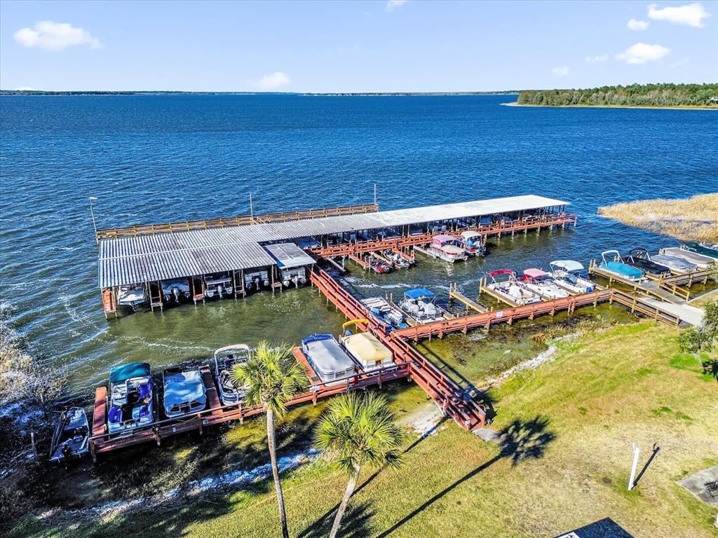 An aerial view of a large wooden boat dock with covered slips on a lake — 113 TROPICAL LANE, LEESBURG, FL