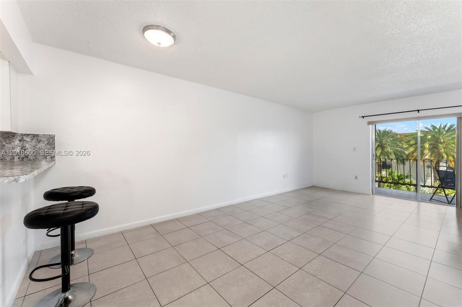 An empty room with white walls, tile flooring, a breakfast bar, and a sliding glass door — 1900 W 54th St # 220, Hialeah FL 33012, HIALEAH, FL
