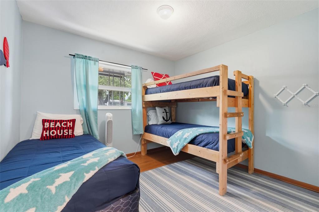 A bedroom features a single bed, a wooden bunk bed, and light blue walls — 12361 114TH STREET, LARGO, FL