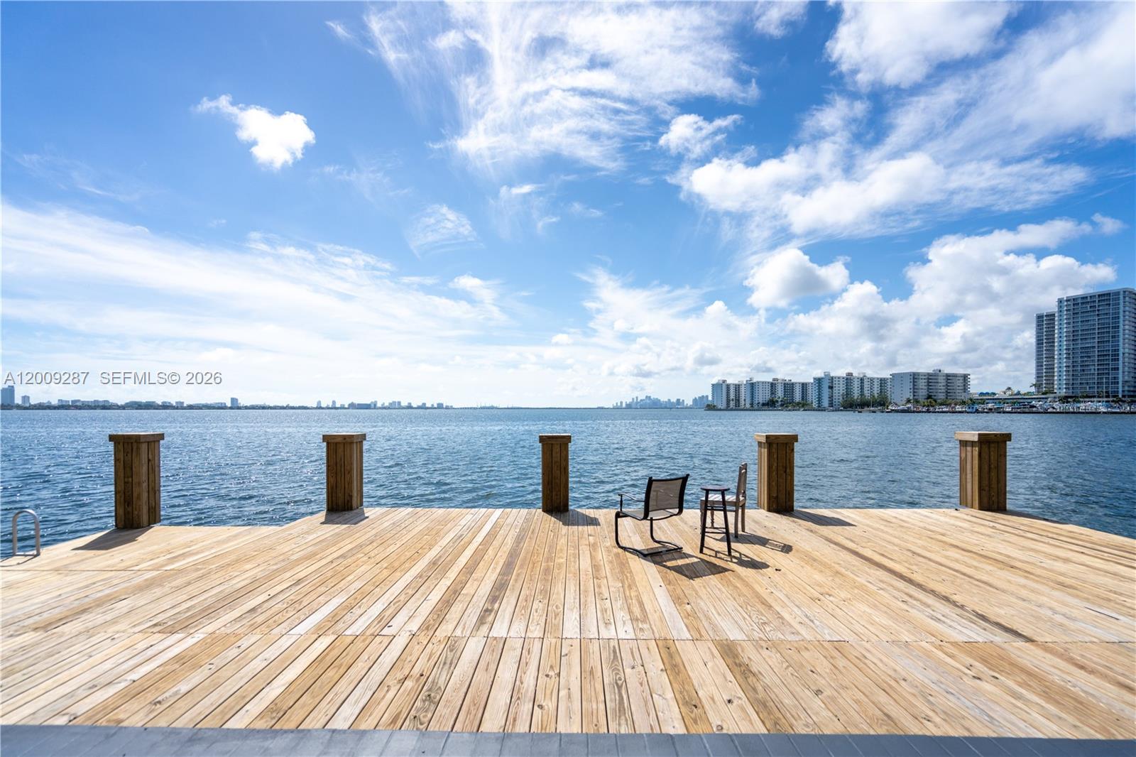 A wooden dock extends over the water with a few chairs and distant city views — 1940 Bay Dr # 11, Miami Beach FL 33141, MIAMI BEACH, FL