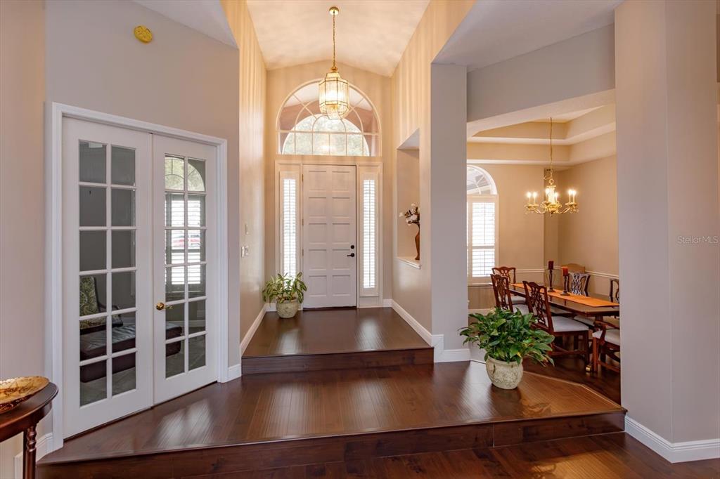 A foyer with dark wood flooring, a raised entry platform, and a dining room beyond — 2381 CHANTILLY TERRACE, OVIEDO, FL