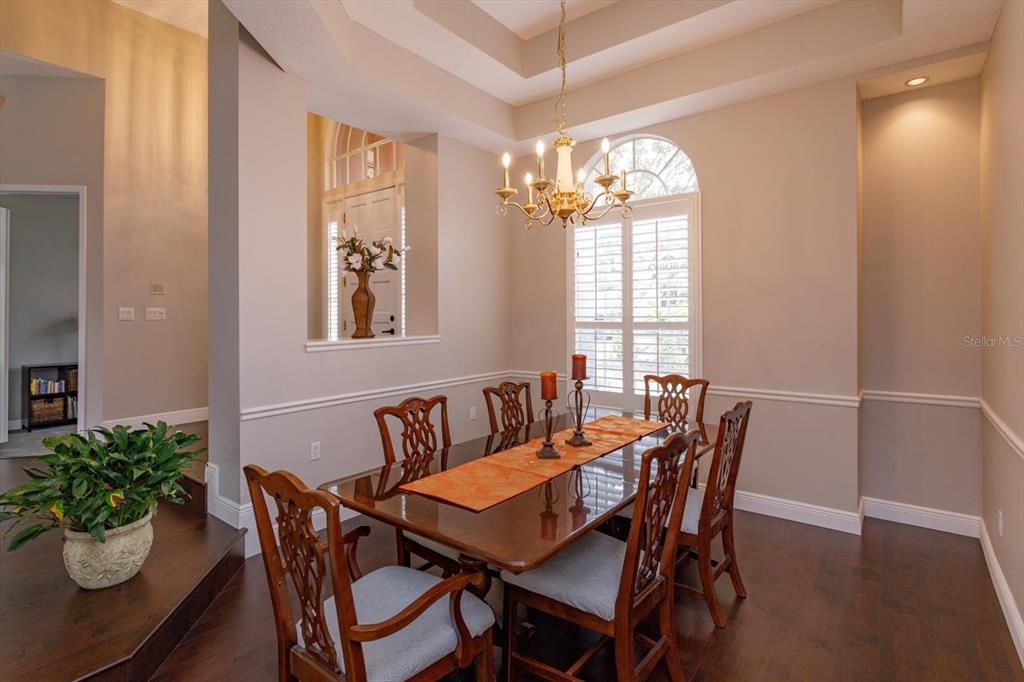 A dining room with a wooden table, six chairs, a chandelier, and dark hardwood floors — 2381 CHANTILLY TERRACE, OVIEDO, FL