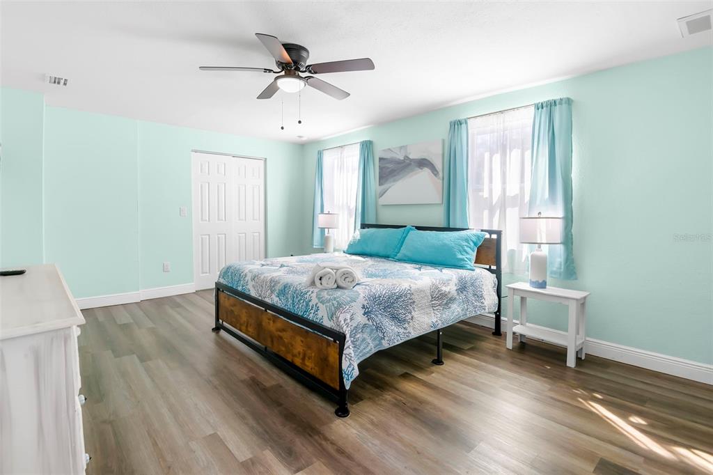 A bedroom features light blue walls, a bed with a coral-patterned quilt, and wood-look flooring — 1613 N MARTIN LUTHER KING JR AVENUE, CLEARWATER, FL