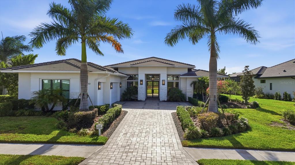 A single-story house with a paved walkway, palm trees, and a tiled roof — 4202 BUTTE TRAIL, BRADENTON, FL