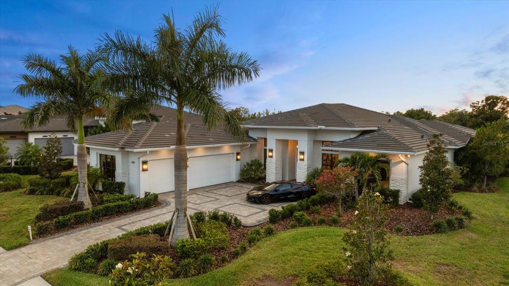 A modern single-story house with a tiled roof, three-car garage, and a black sports car — 4202 BUTTE TRAIL, BRADENTON, FL