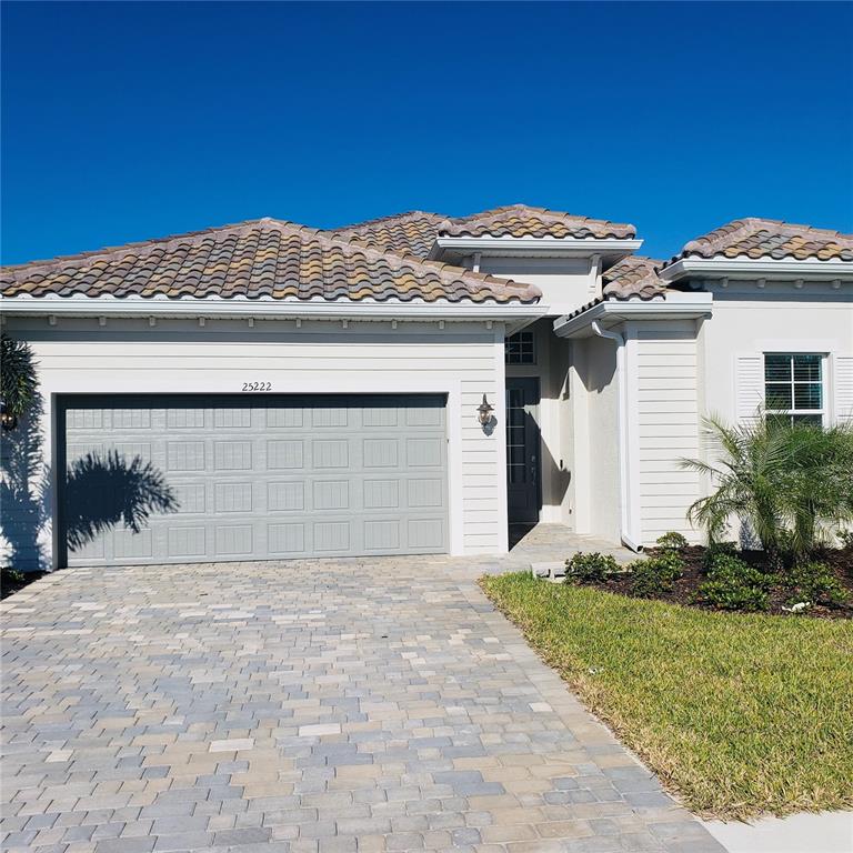A single-story house with a gray garage door, tiled roof, and a paved driveway — 25222 KEYGRASS COURT, PUNTA GORDA, FL