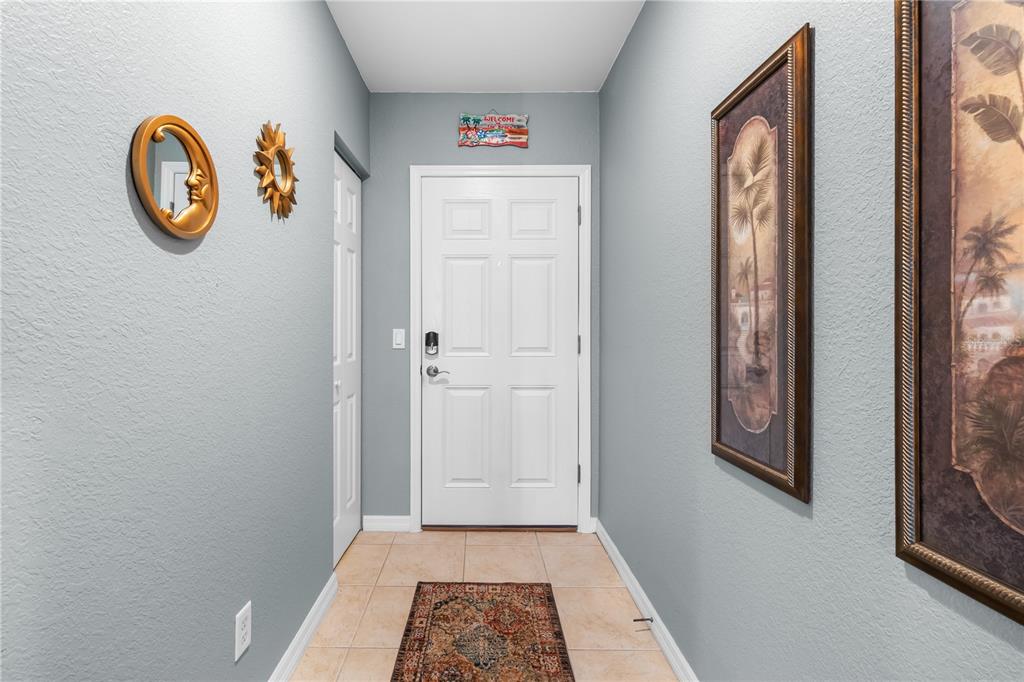 An entryway features a white front door, light gray walls, tile flooring, and wall decor — 8405 PLACIDA ROAD UNIT 206, PLACIDA, FL
