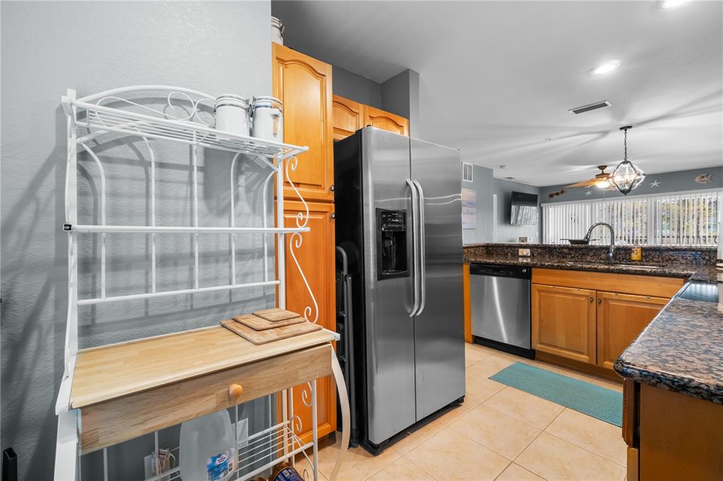 A kitchen features wood cabinets, granite countertops, stainless steel appliances, and a white metal baker's rack — 8405 PLACIDA ROAD UNIT 206, PLACIDA, FL