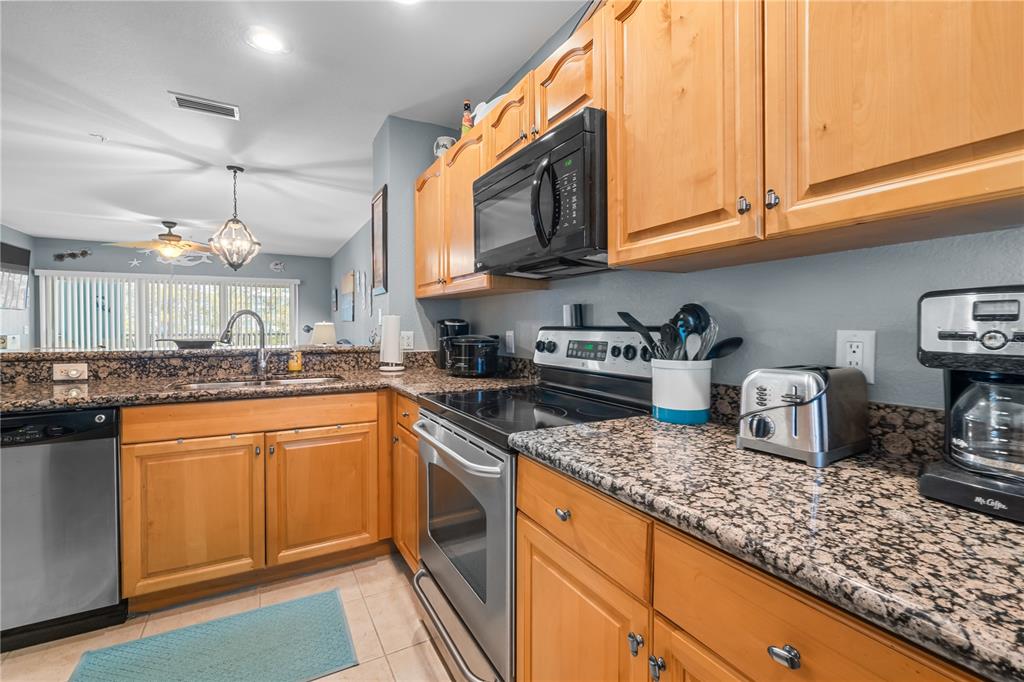 A kitchen features wood cabinets, granite countertops, stainless steel appliances, and a tile floor — 8405 PLACIDA ROAD UNIT 206, PLACIDA, FL
