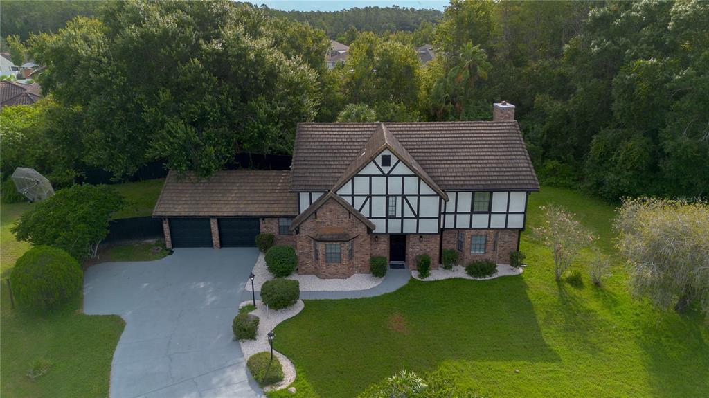 An aerial view shows a two-story Tudor-style brick house with a driveway and surrounding lawn — 2540 ALBANY DRIVE, KISSIMMEE, FL