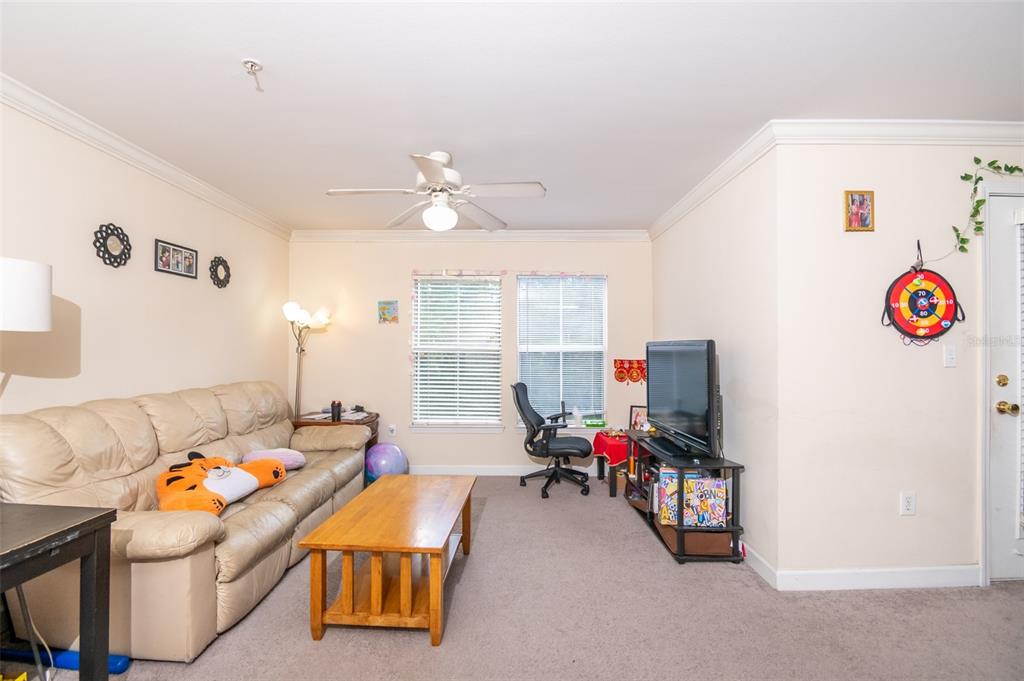 A living room features a beige leather sofa, a wooden coffee table, and a television — 18113 BRIDLE CLUB DRIVE, TAMPA, FL