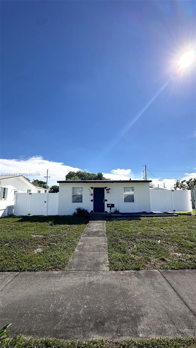A single-story white house with a dark front door and a concrete walkway — 550 NW 15th Ct, Pompano Beach FL 33060, POMPANO BEACH, FL