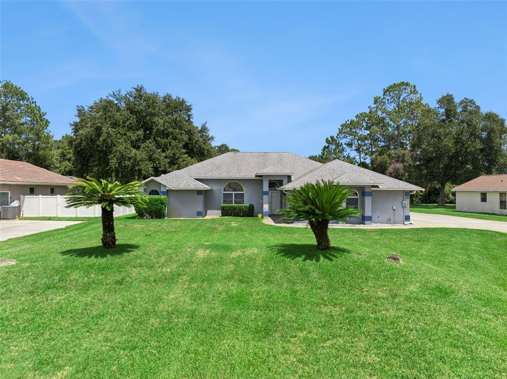 A single-story house with a gray exterior, a shingled roof, and two palm trees in front — 23 WELLSTREAM LANE, PALM COAST, FL