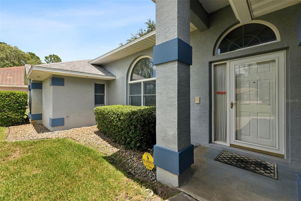 The exterior of a gray house features a front porch, a white door, and landscaping — 23 WELLSTREAM LANE, PALM COAST, FL
