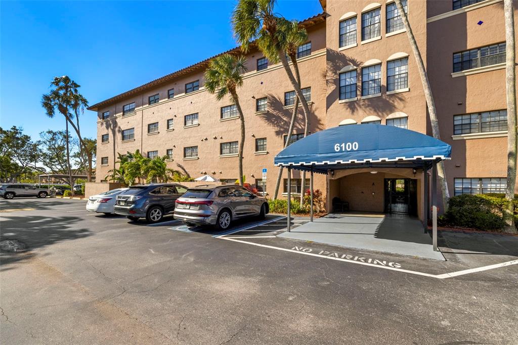 An exterior view of a multi-story apartment building with a blue awning over the entrance — 6100 GULFPORT BOULEVARD S UNIT 414, GULFPORT, FL