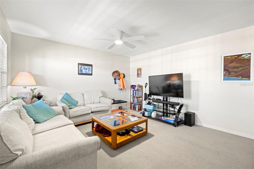 A living room features light-colored sofas, a wooden coffee table, and a wall-mounted television — 6100 GULFPORT BOULEVARD S UNIT 414, GULFPORT, FL