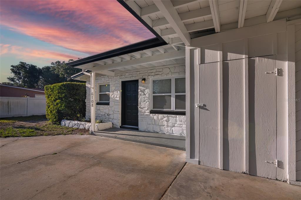 A white stone house exterior features a black front door and a concrete driveway — 6108 BEAR LAKE TERRACE, APOPKA, FL