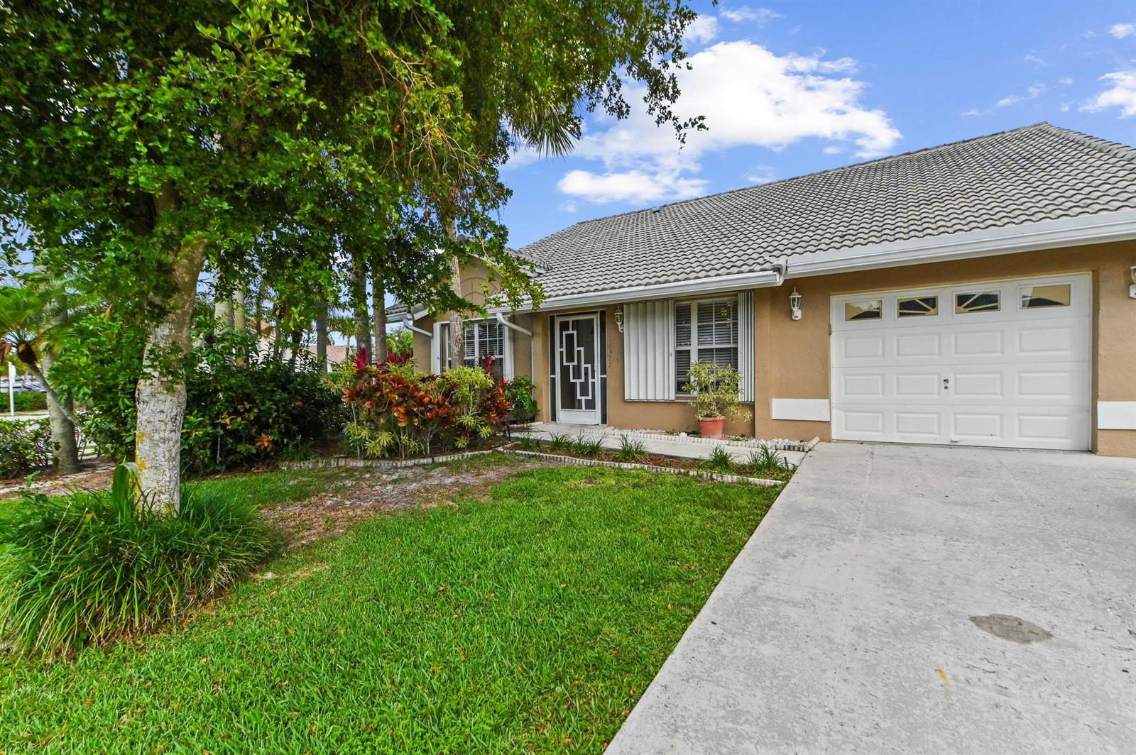 A single-story house with a tan exterior, a gray tile roof, and a concrete driveway — 18377 Fresh Lake Way, Boca Raton FL 33498, BOCA RATON, FL