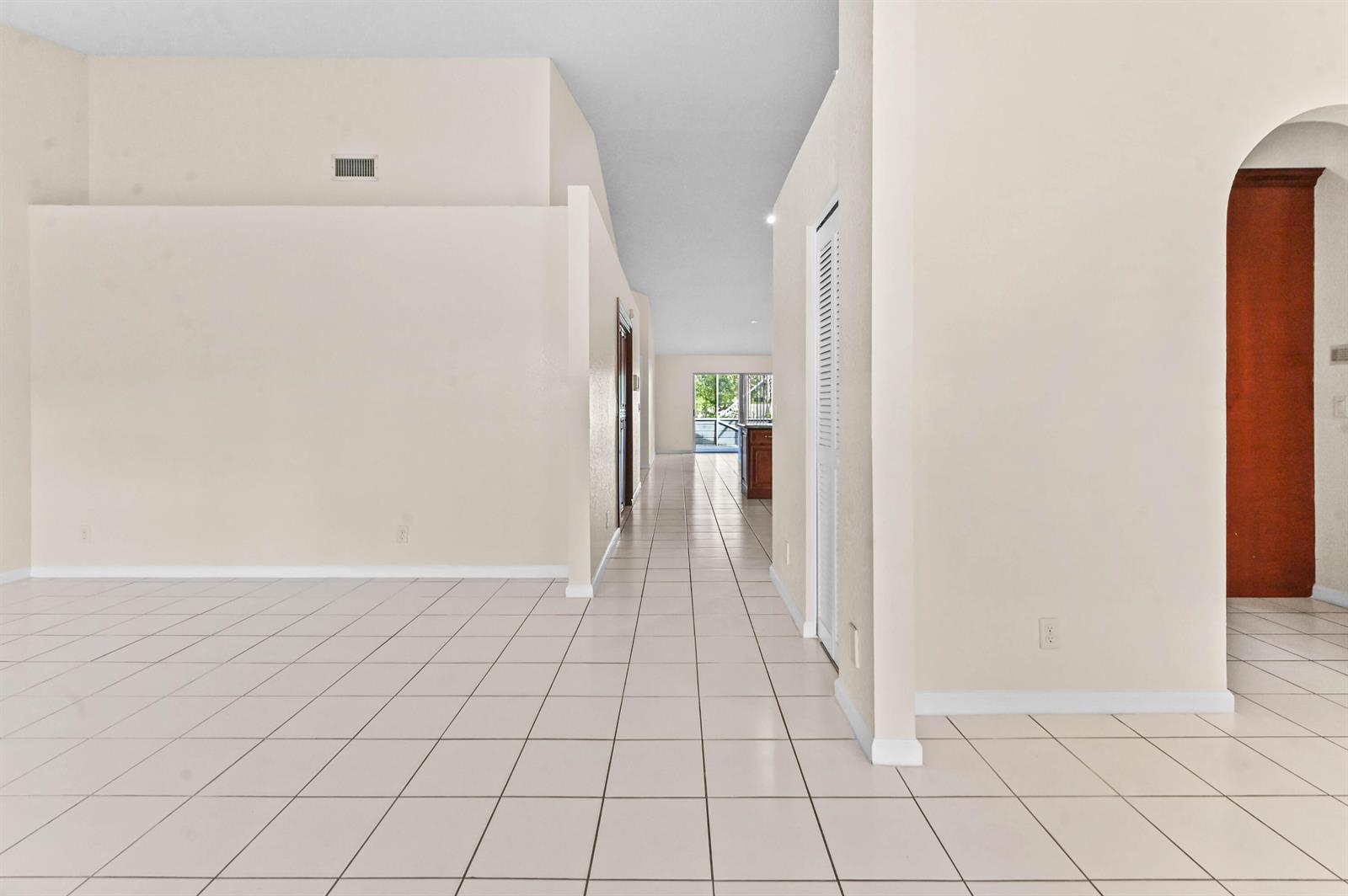 A tiled hallway leads from an open living area toward a kitchen and exterior view — 18377 Fresh Lake Way, Boca Raton FL 33498, BOCA RATON, FL