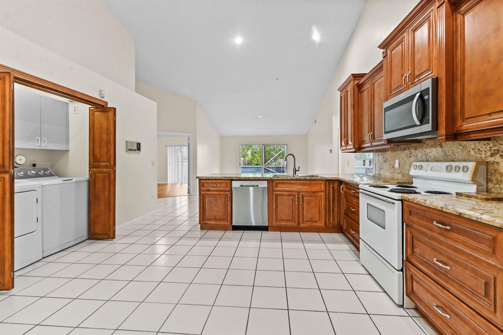 A kitchen with wood cabinets, granite countertops, white appliances, and tiled floors — 18377 Fresh Lake Way, Boca Raton FL 33498, BOCA RATON, FL