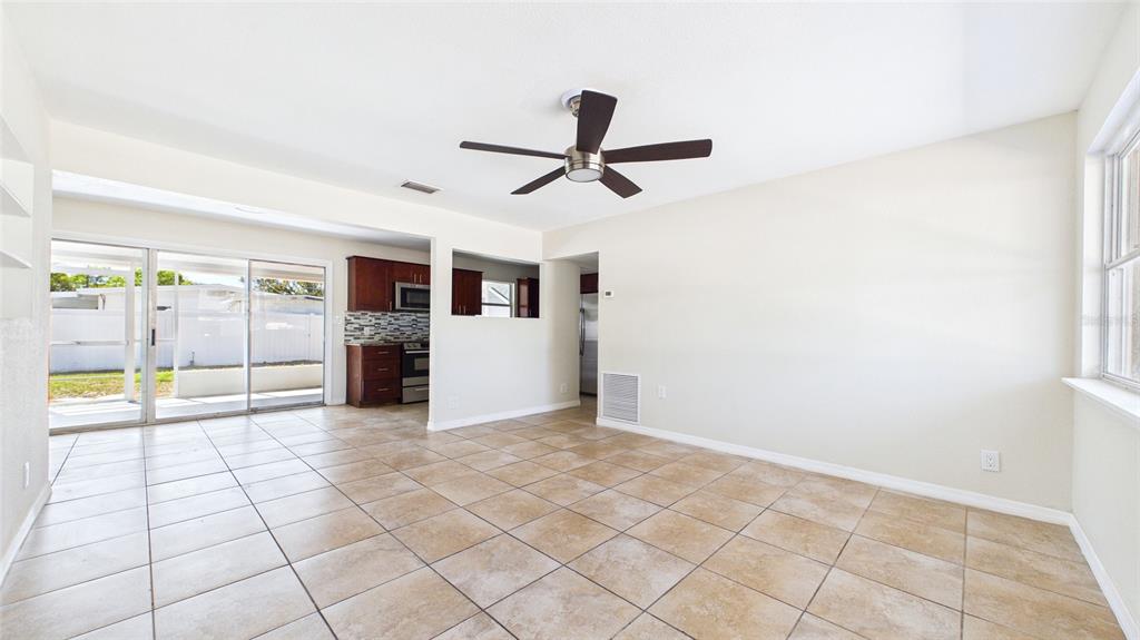 A tiled dining area features a ceiling fan, a pass-through window, and sliding glass doors — 4418 W FAIRVIEW HEIGHTS, TAMPA, FL