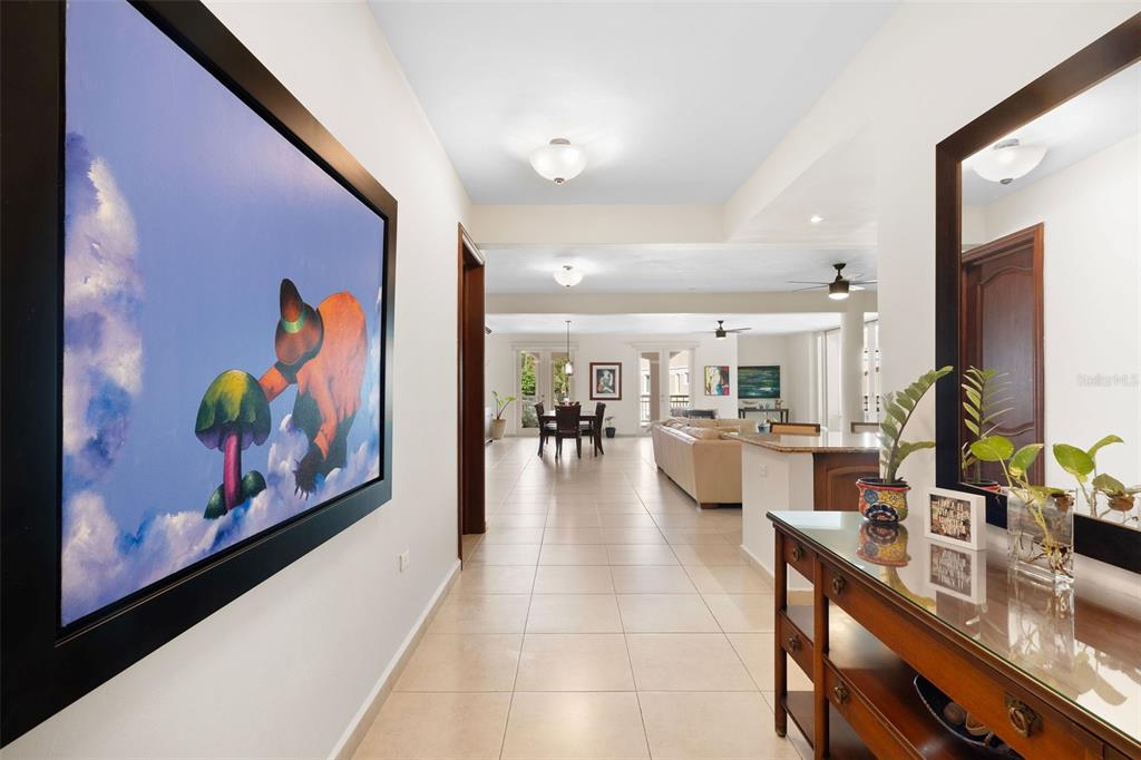 A tiled hallway leads into an open-concept living and dining area with a large wall painting — 355 HARBOUR DRIVE UNIT 2C South, HUMACAO, PR