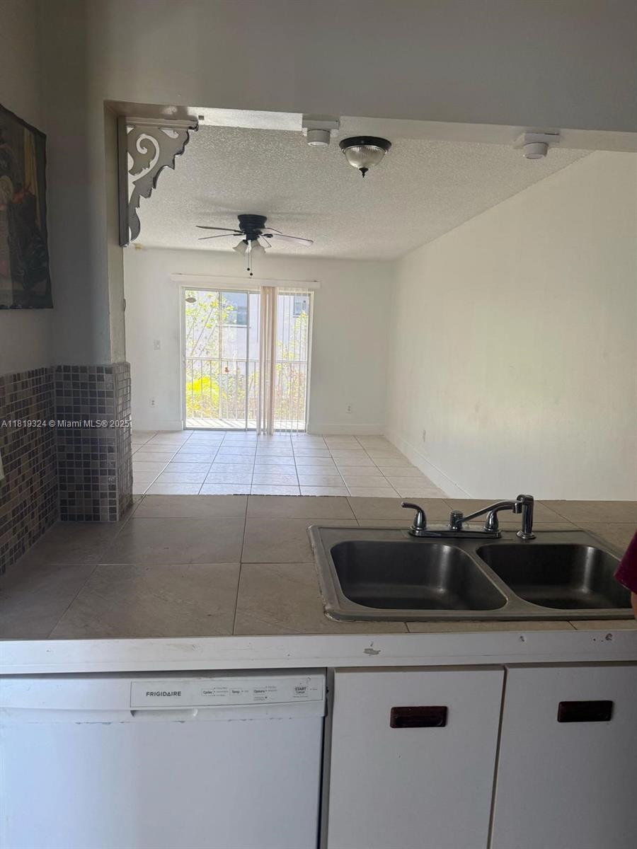 A kitchen sink and dishwasher overlook a living area with tile floors and a balcony — 438 NE 210th Cir Ter # 4B, Miami FL 33179, MIAMI, FL