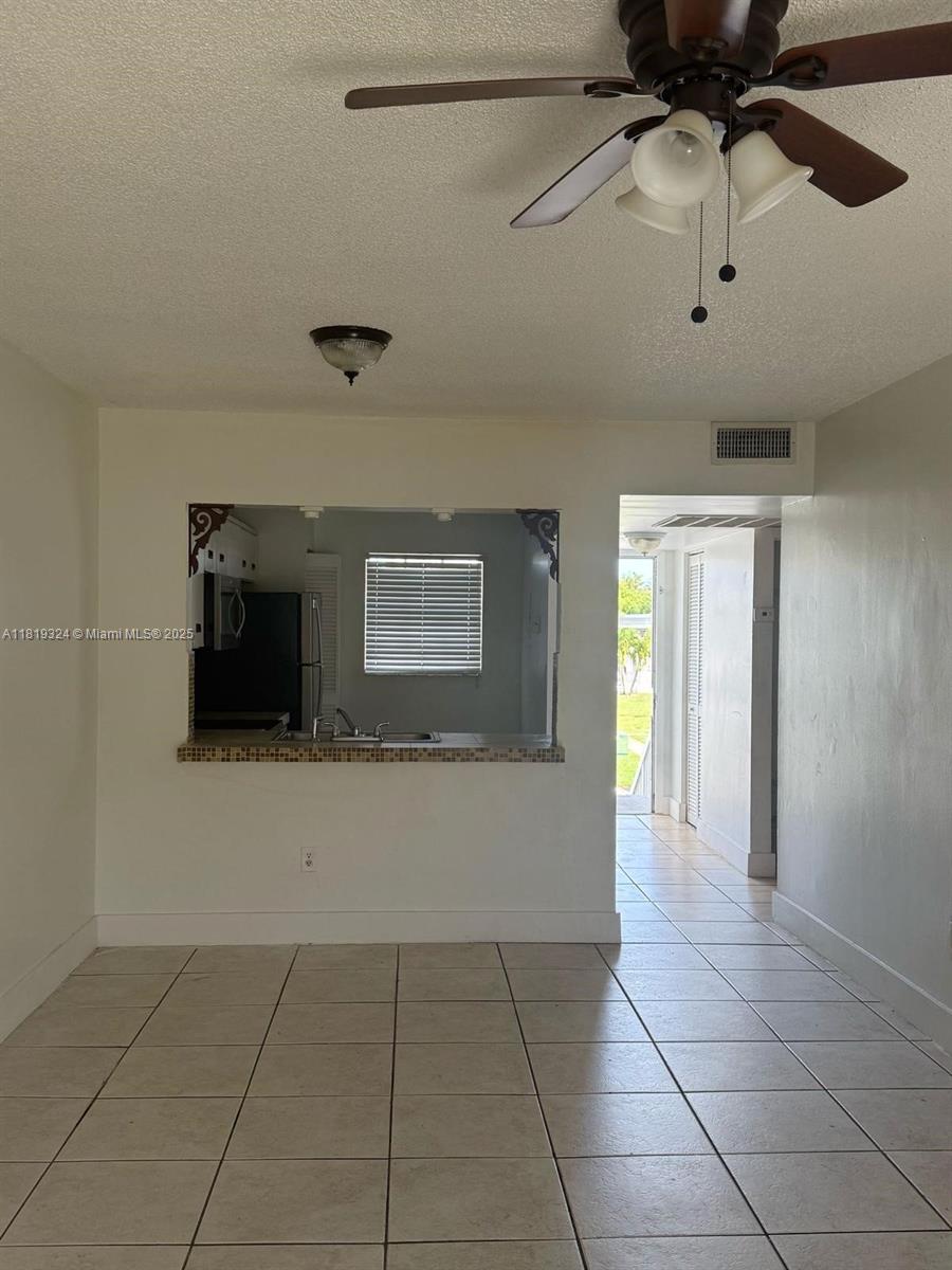 A dining area with tile floors features a ceiling fan and a kitchen pass-through window — 438 NE 210th Cir Ter # 4B, Miami FL 33179, MIAMI, FL