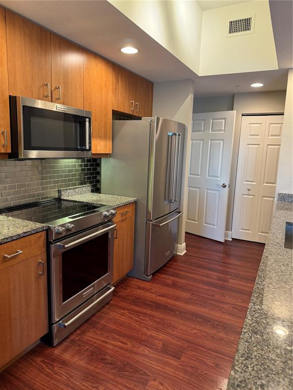 A kitchen features wood cabinets, stainless steel appliances, granite countertops, and a subway tile backsplash — 800 N TAMIAMI TRAIL UNIT 211, SARASOTA, FL