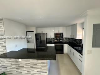 A modern kitchen features white cabinets, black granite countertops, and a tiled breakfast bar — MIAMI, FL