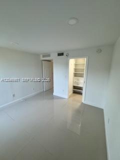 An empty room with light-colored tile flooring, recessed lighting, and an open walk-in closet — MIAMI, FL