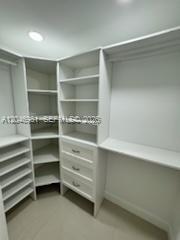 A white walk-in closet features built-in shelving, a corner unit, and a set of drawers — MIAMI, FL