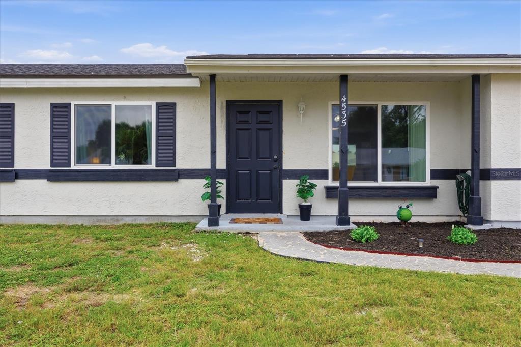 A single-story house exterior features a dark front door, shutters, and a stone walkway — 4535 MONGITE ROAD, NORTH PORT, FL