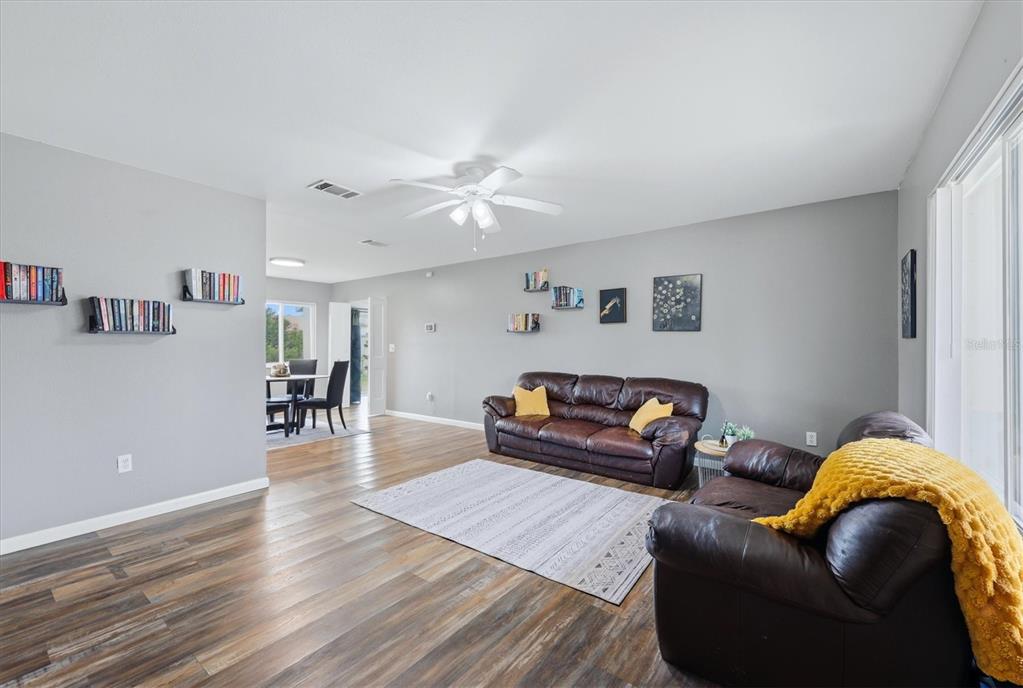 A living room with wood-look flooring, gray walls, brown leather sofas, and a ceiling fan — 4535 MONGITE ROAD, NORTH PORT, FL