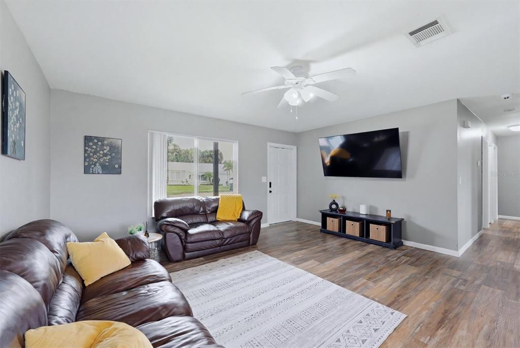 A living room features brown leather sofas, a television, and wood-look flooring — 4535 MONGITE ROAD, NORTH PORT, FL