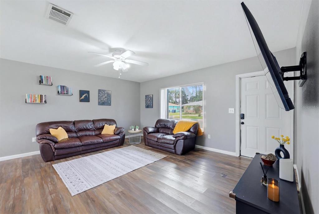 A living room features gray walls, wood-look flooring, two brown leather sofas, and a television — 4535 MONGITE ROAD, NORTH PORT, FL