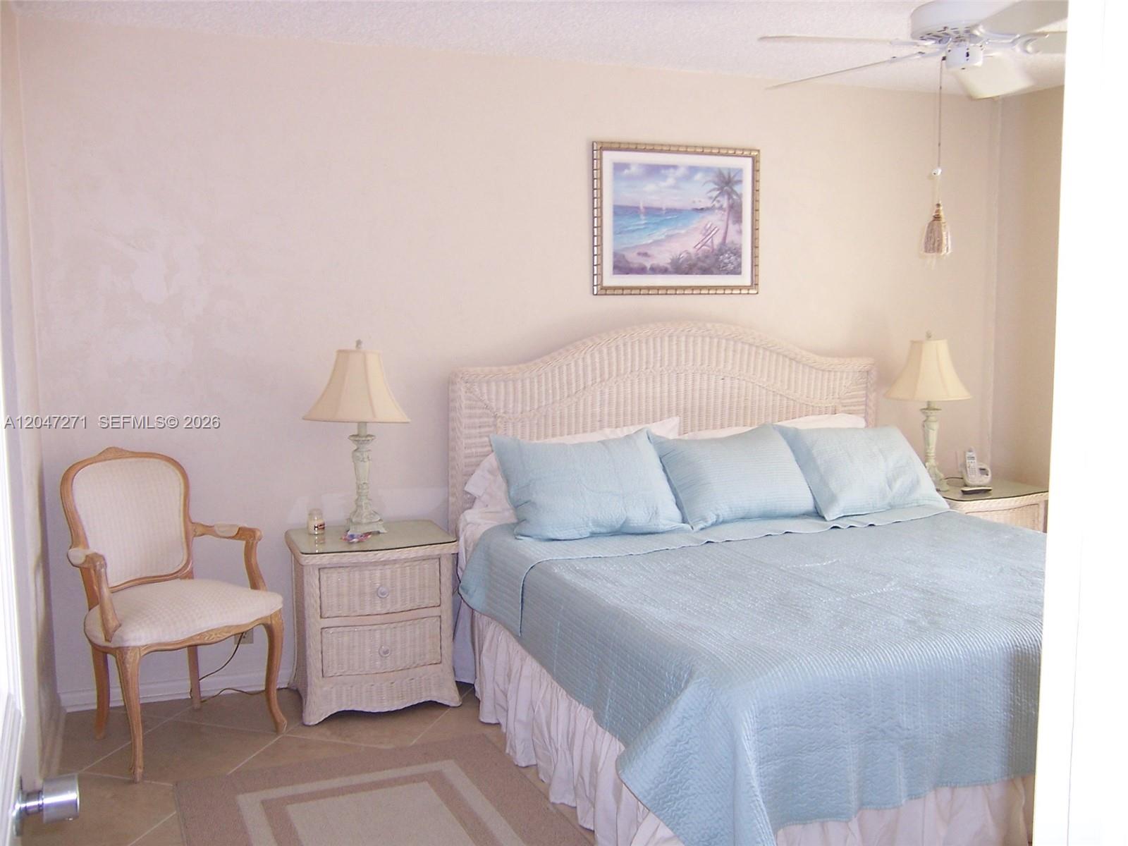 A bedroom features a wicker headboard, light blue bedding, two nightstands, and a side chair — JUPITER, FL