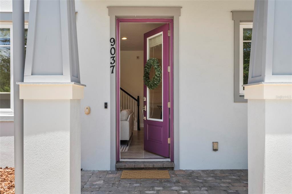 A bright purple front door with a wreath stands open to a home interior — 9037 LAUREATE BOULEVARD, ORLANDO, FL