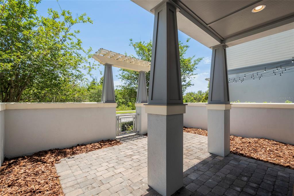 A paved patio features a pergola, gray columns, and a small metal gate — 9037 LAUREATE BOULEVARD, ORLANDO, FL