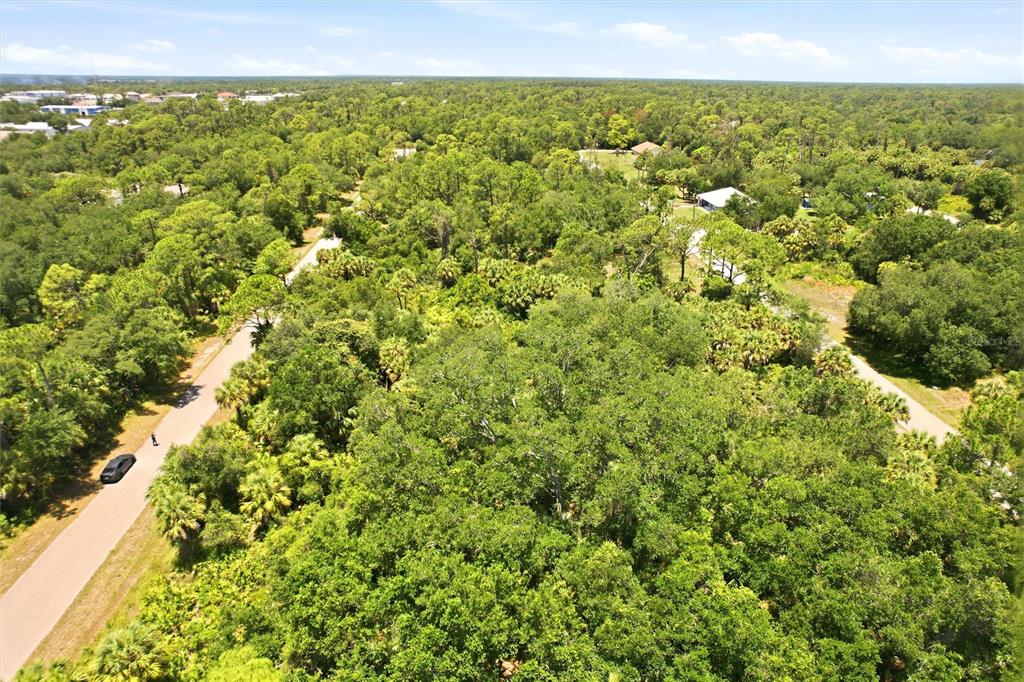 An aerial view shows a wooded lot with a paved road and scattered residential homes — 18426 SAGAMORE AVENUE, PORT CHARLOTTE, FL