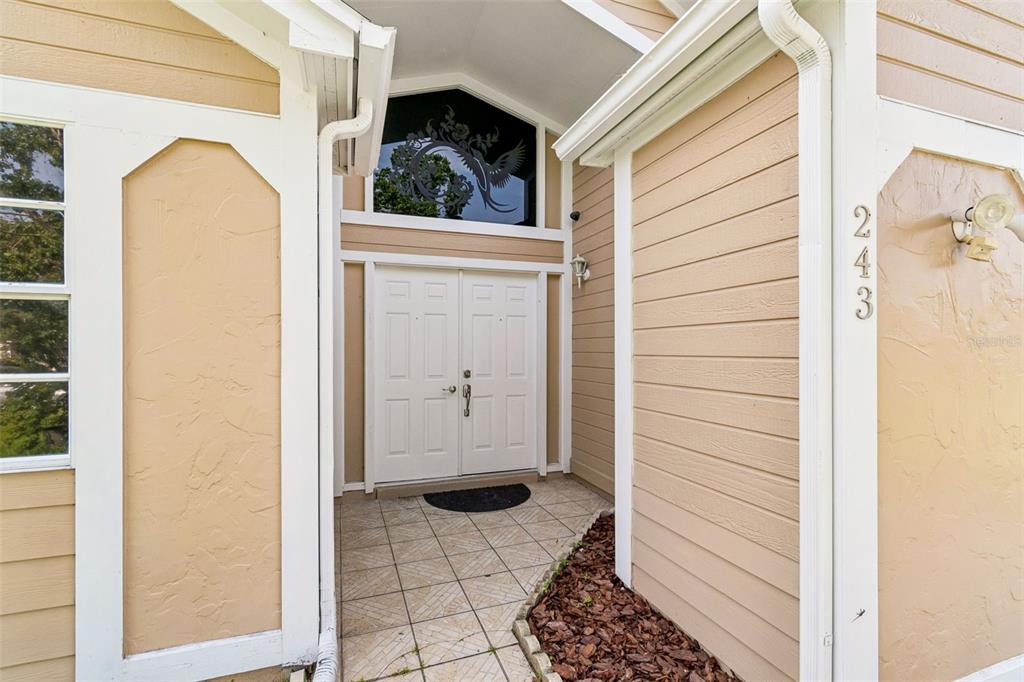 The exterior entrance features double white doors, a decorative transom window, and tan siding — 243 RAPSCALLION COURT, ORLANDO, FL