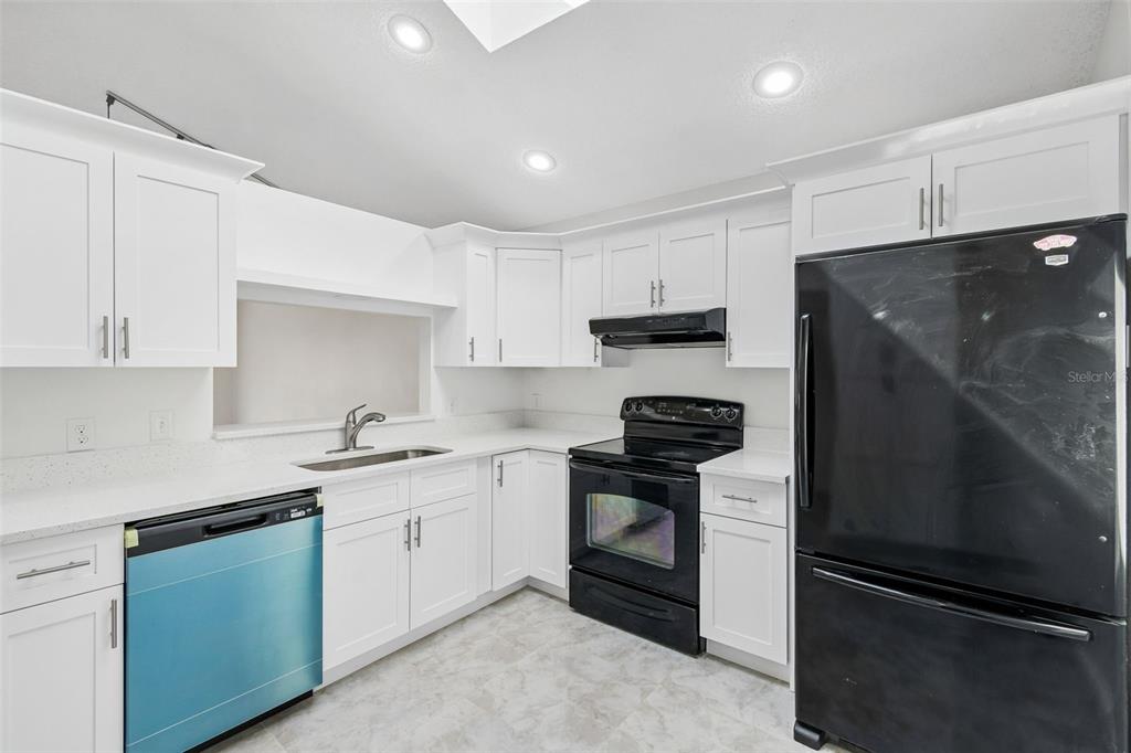 A kitchen features white cabinets, black appliances, a stainless steel sink, and light-colored countertops — 243 RAPSCALLION COURT, ORLANDO, FL