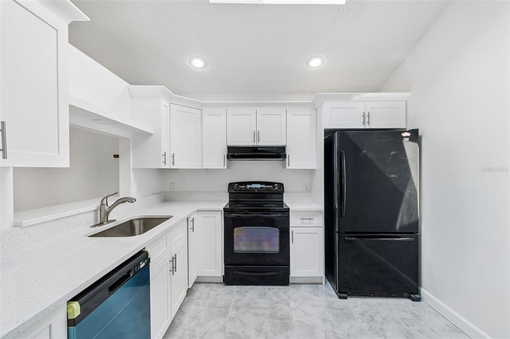 A kitchen features white cabinets, white countertops, black appliances, and light-colored tile flooring — 243 RAPSCALLION COURT, ORLANDO, FL